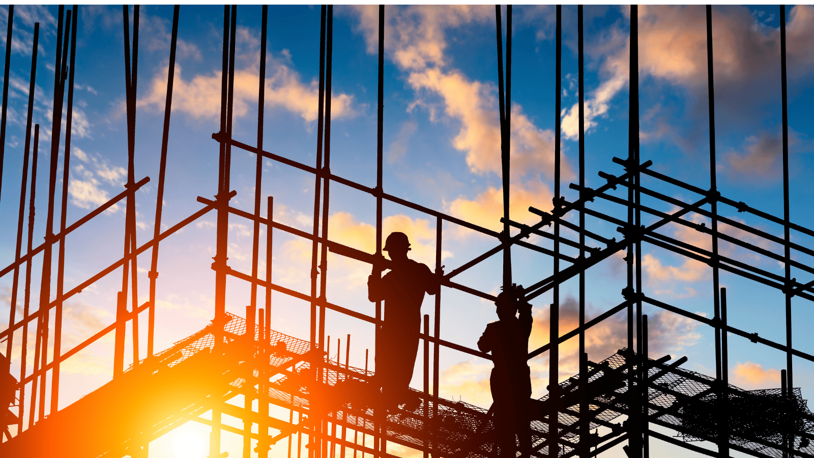 Silhouettes of construction workers on scaffolding during sunset, with blue sky and clouds in the background.