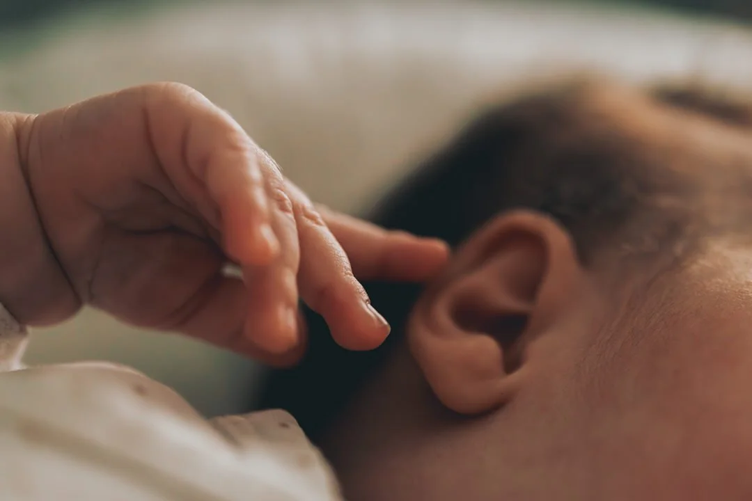 Close-up of a person gently touching their ear with their fingers.