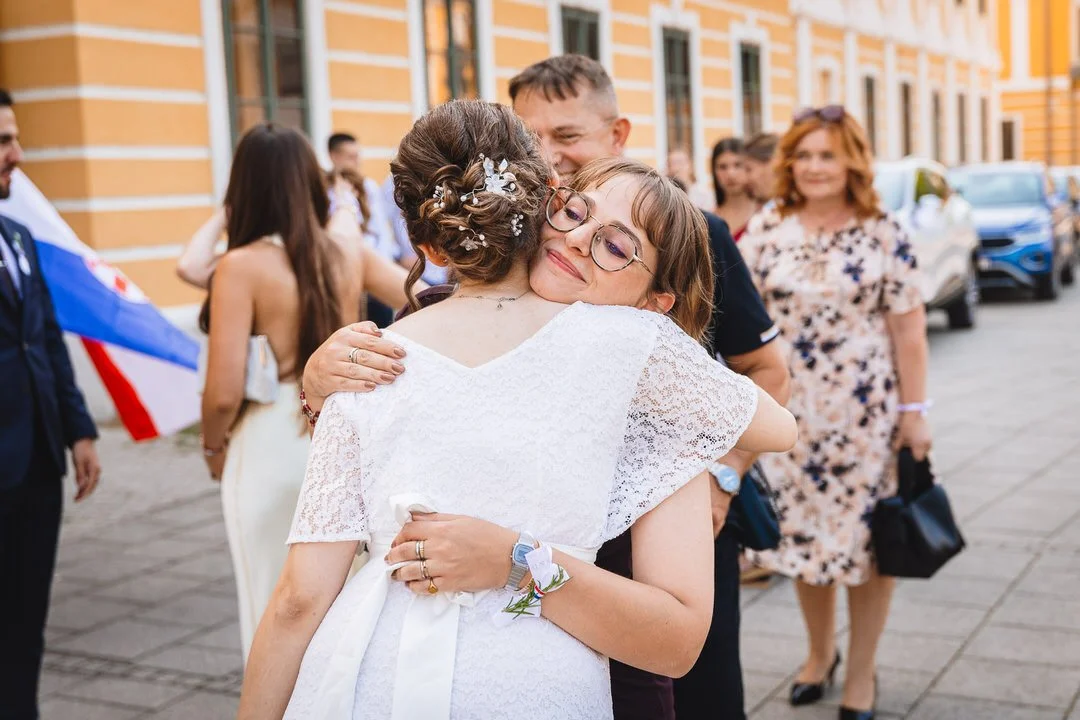 Wedding guests hugging and celebrating outside Eltz Castle in Vukovar, Croatia, during a joyful wedding celebration.