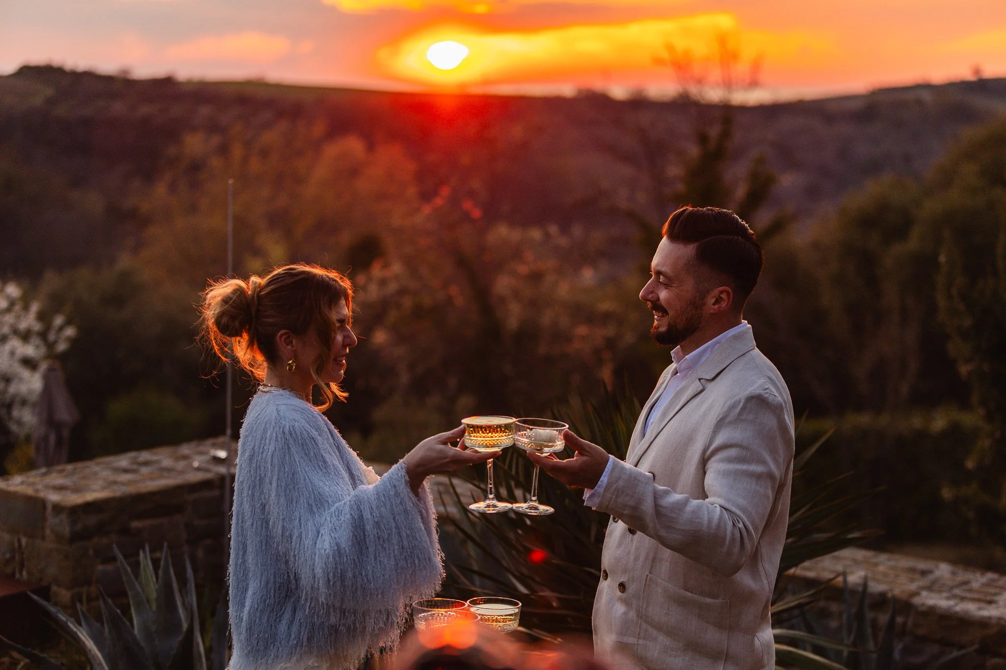 A couple smiles at each other as they share glasses of champagne during sunset wedding in san canzian, Istria, Croatia