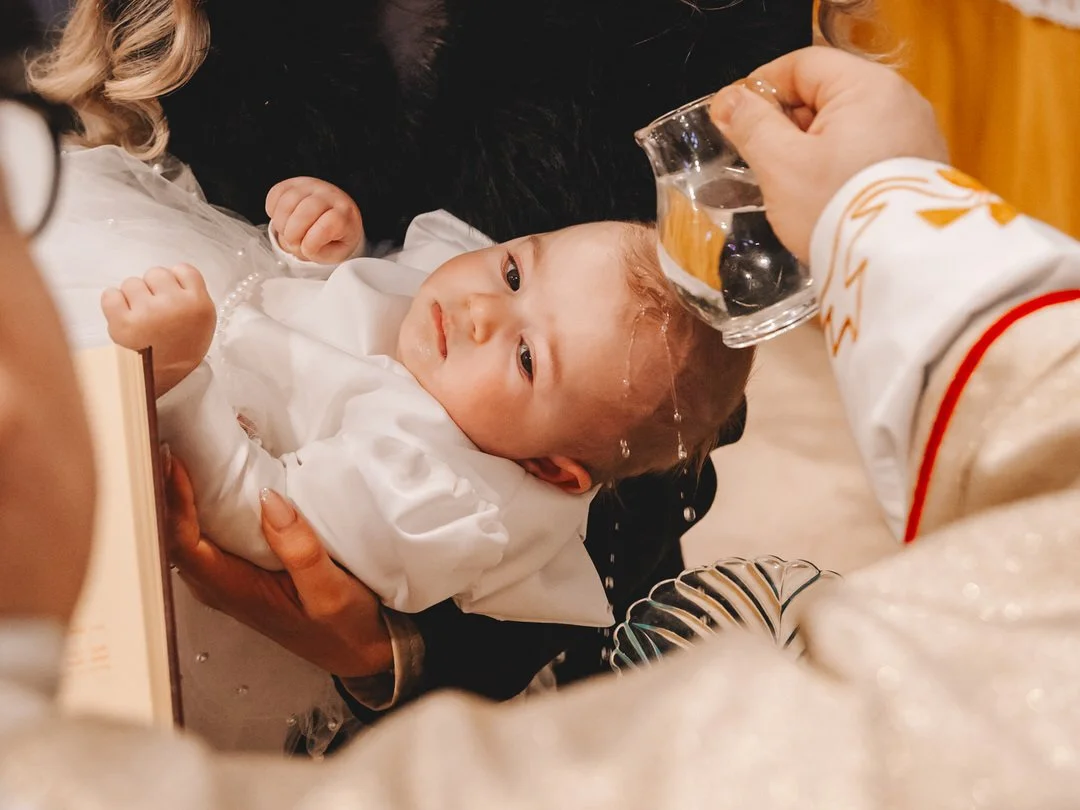 Baby being baptized with water poured on his head 