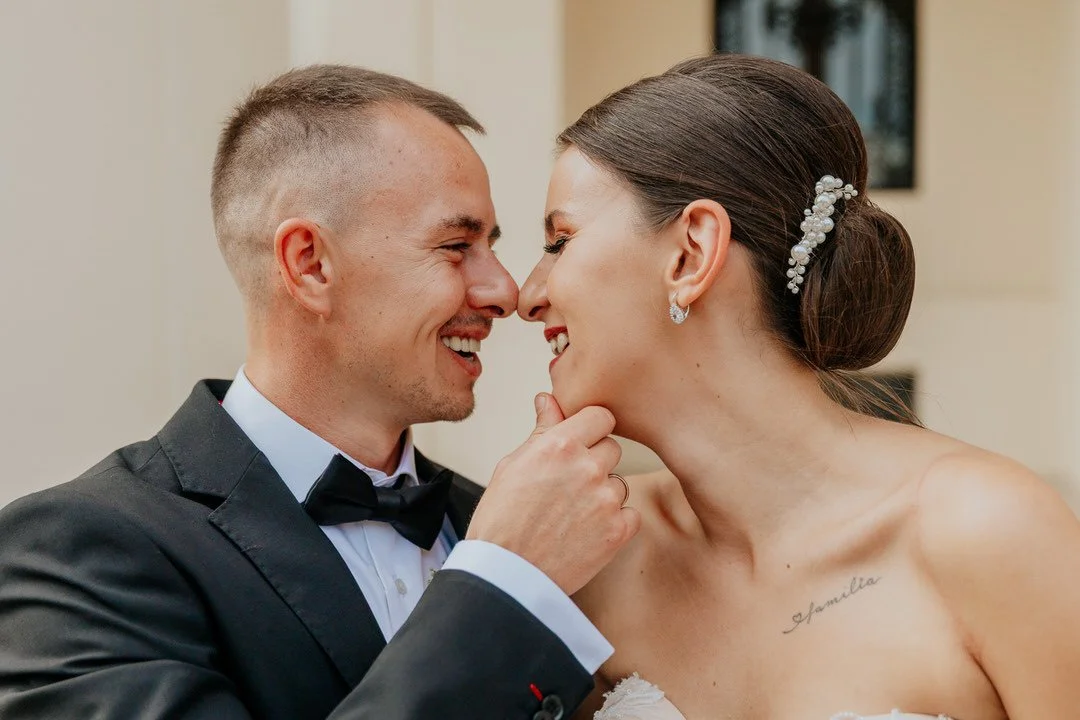 A bride and groom are close, smiling, and touching noses at their wedding in Našice Crpatoa, with the groom's hand on the bride's chin.