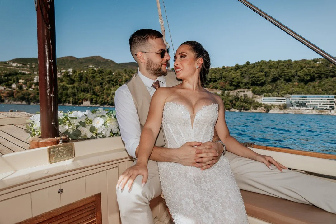 Newlywed couple embracing on a boat during a wedding photoshoot on Kvarner Bay near Opatija and Volosko, surrounded by open water and a distant shoreline.