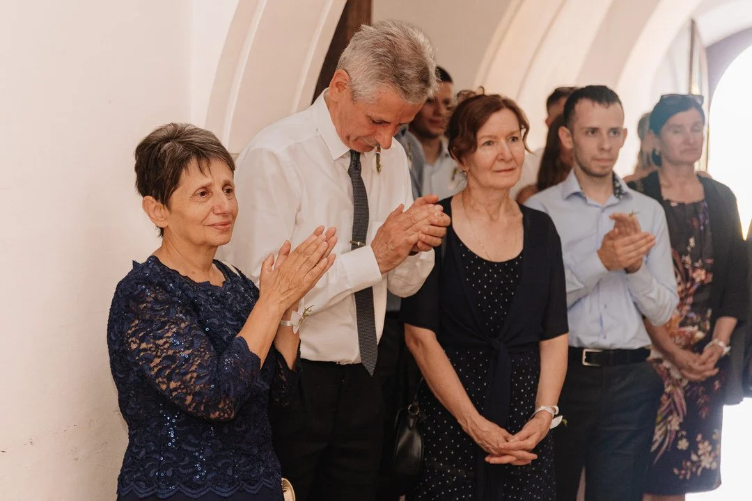Group of people standing close together, some clapping, in a religious or ceremonial setting.