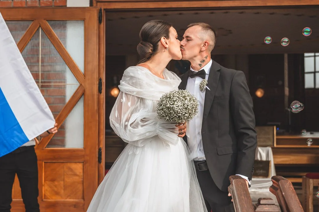 Bride and groom kissing at their wedding reception, with the bride holding a bouquet of baby's breath flowers.