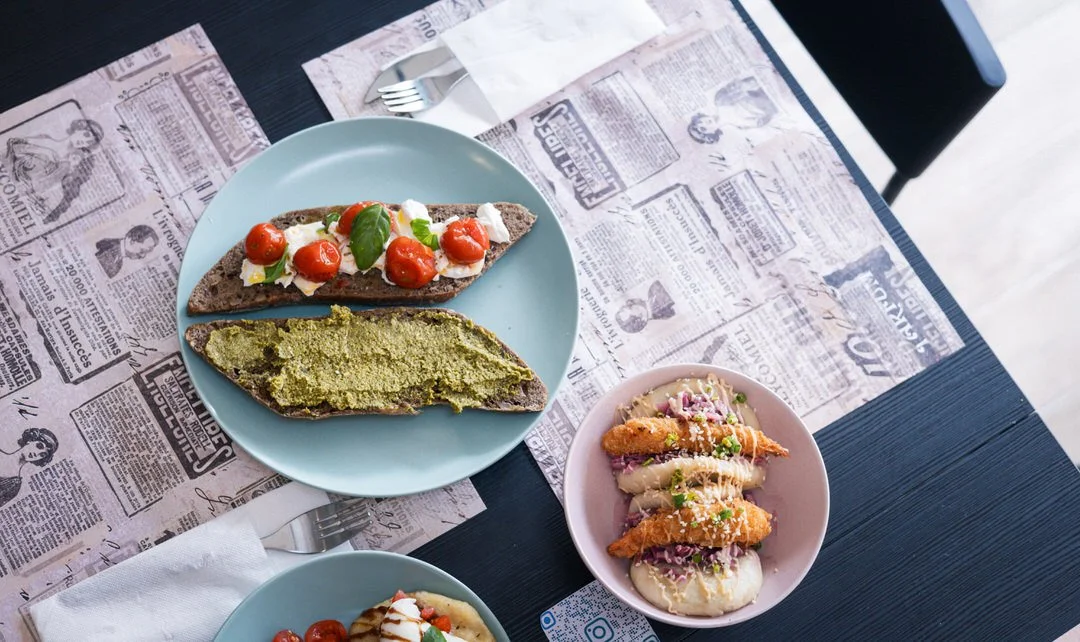 A table with two plates of food and a smaller bowl, including bread with toppings and fish buns, at a Yumii brunch in Zagreb, Croatia.