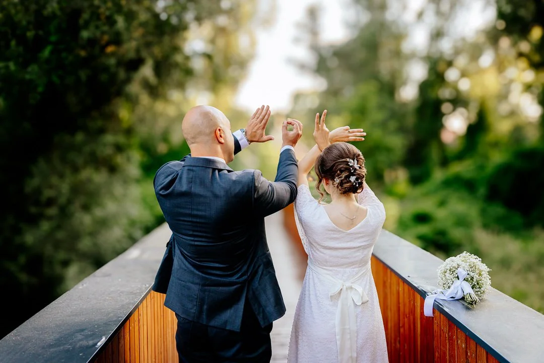 Bride and groom celebrating love on a bridge with a bouquet of flowers beside them.