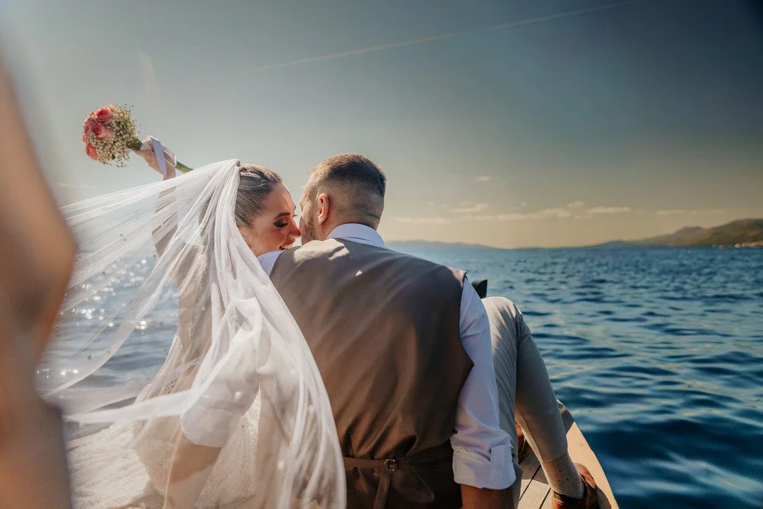 Bride and groom on a boat cruising along the Opatija and Volosko coast on Kvarner Bay, smiling at each other during their wedding session.
