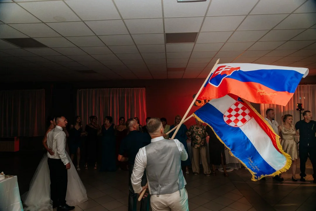 People at a celebration holding Croatian and Slovak flags in a dimly lit event hall.