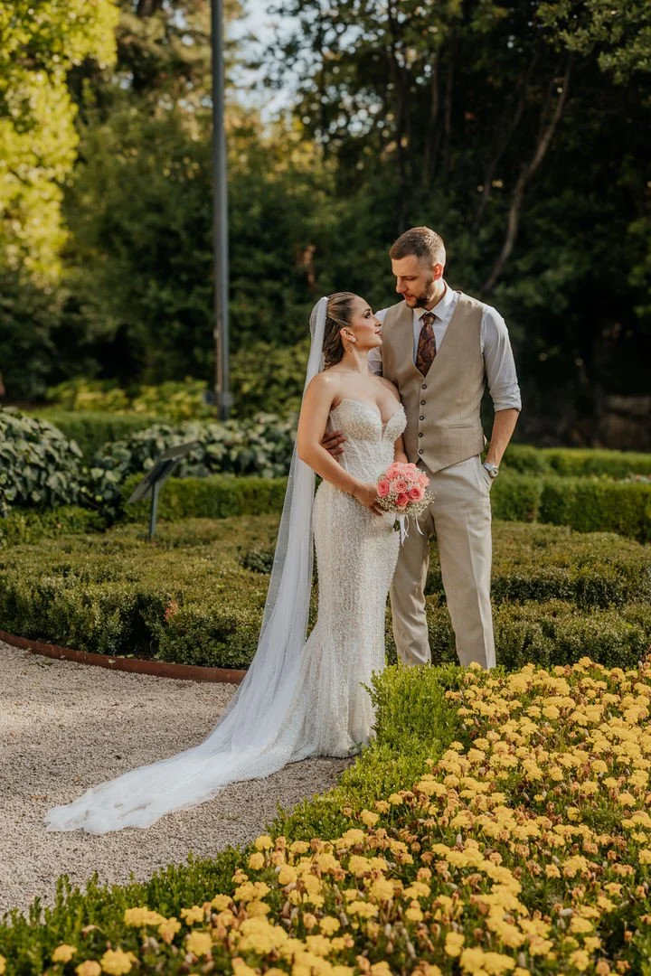 Bride and groom looking into each other's eyes in Park Angiolina, Opatija, Kvarner, with lush green trees and bushes surrounding their outdoor wedding.