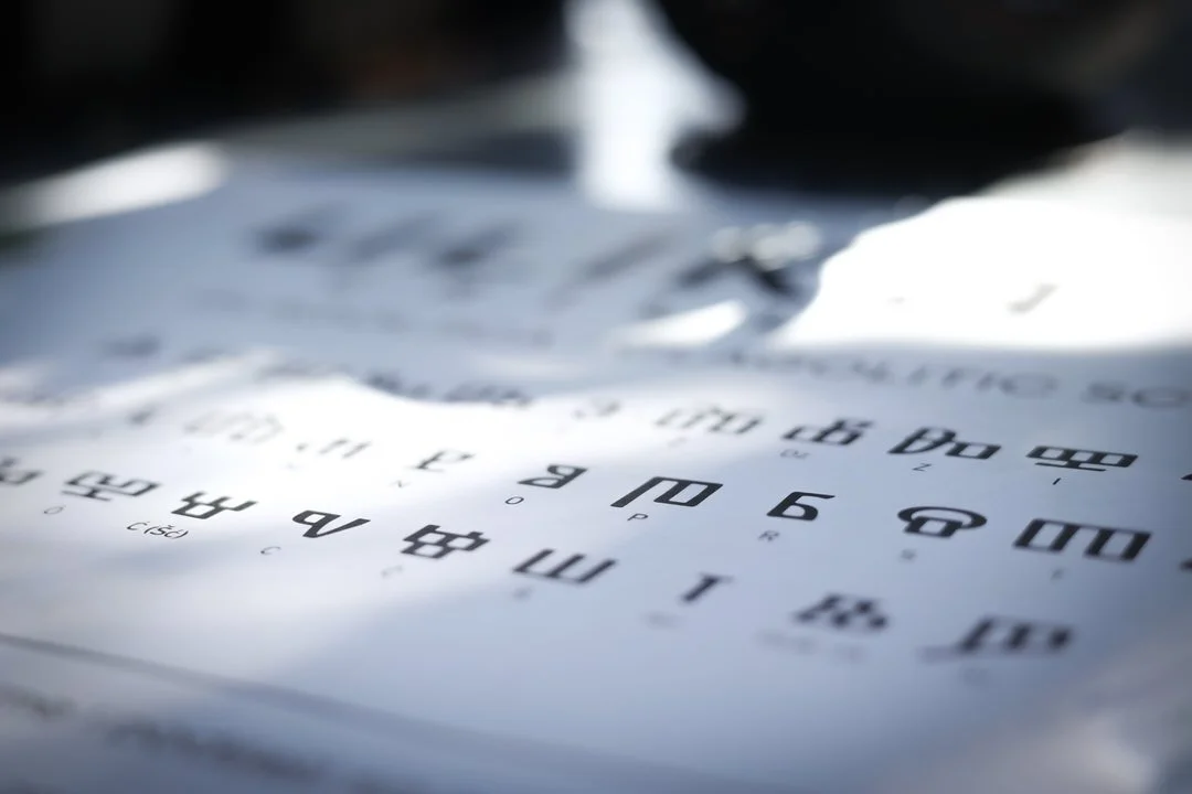 A close-up of a paper with large print letters and numbers, likely a chart or a guide, resting on a flat surface with shadows cast on it.