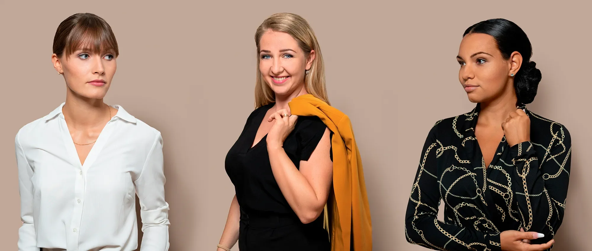 Drei Frauen stehen nebeneinander vor einem hellbeigen Hintergrund. Die Frau auf der linken trägt eine weiße Bluse, die Frau in der Mitte trägt ein schwarzes Oberteil mit einer orangefarbenen Jacke über der Schulter, und die Frau auf der rechten trägt