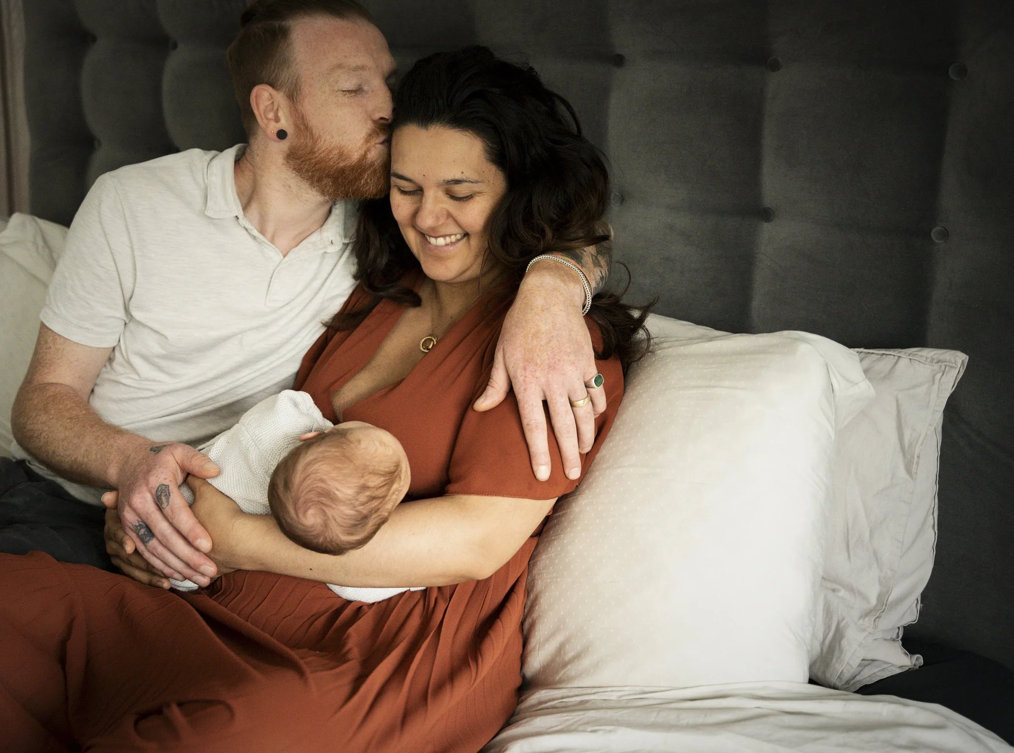 Newborn fotografie aan huis in Wagenberg. Een gezin met een pasgeboren baby op een bed, plezier en liefde uitstralend.