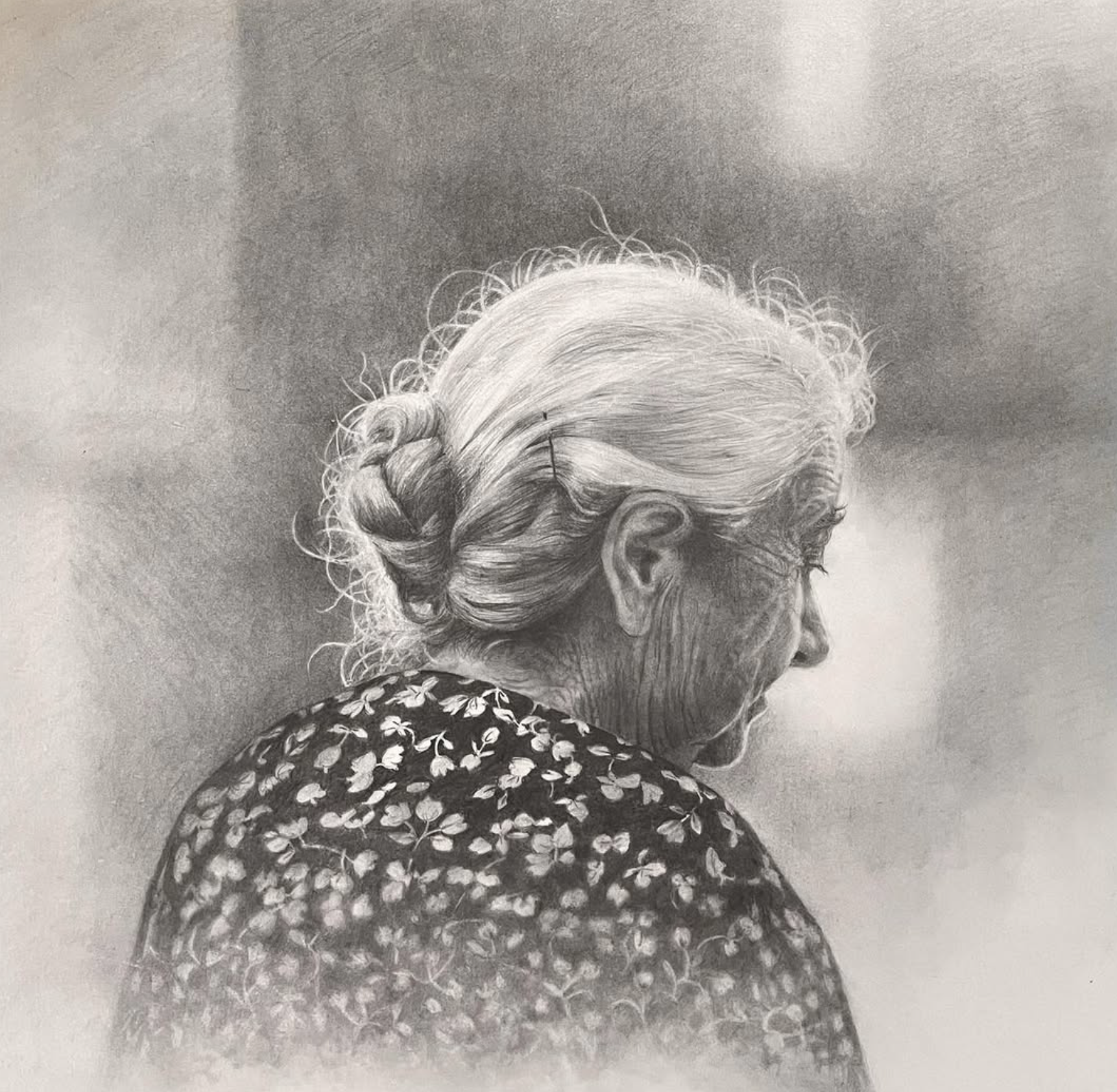 Black and white portrait of an elderly woman with her hair in a bun, wearing glasses and a floral patterned top.