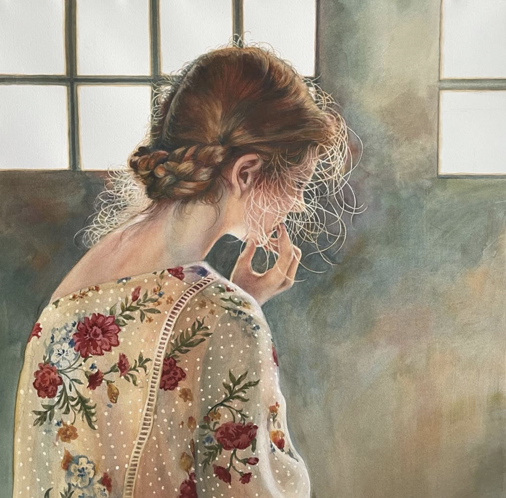 A woman with red hair styled in a braid, wearing a floral-patterned robe, is looking down with her hand near her face near a window with square panes.