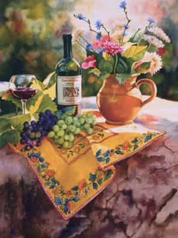 A still life scene featuring a bouquet of mixed flowers in a terracotta pitcher, a bottle of wine, a glass of red wine, and bunches of green and purple grapes on a colorful embroidered tablecloth outdoors.
