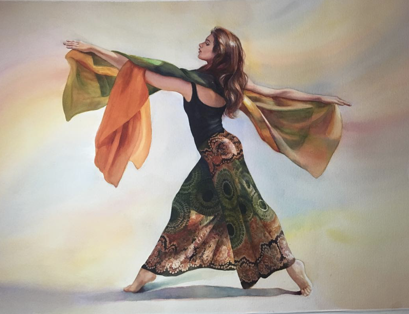 A woman in a black top and colorful, patterned flowing skirt dances with large, colorful, flowing fabric draped around her arms, against a soft, blended background.