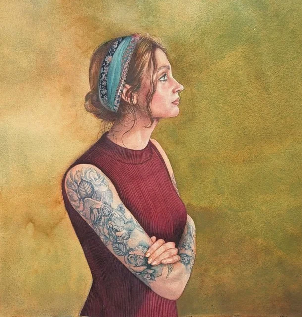 A woman with colorful tattoos on her arms, wearing a sleeveless maroon top and a multicolored headband, standing in profile against a textured green background.
