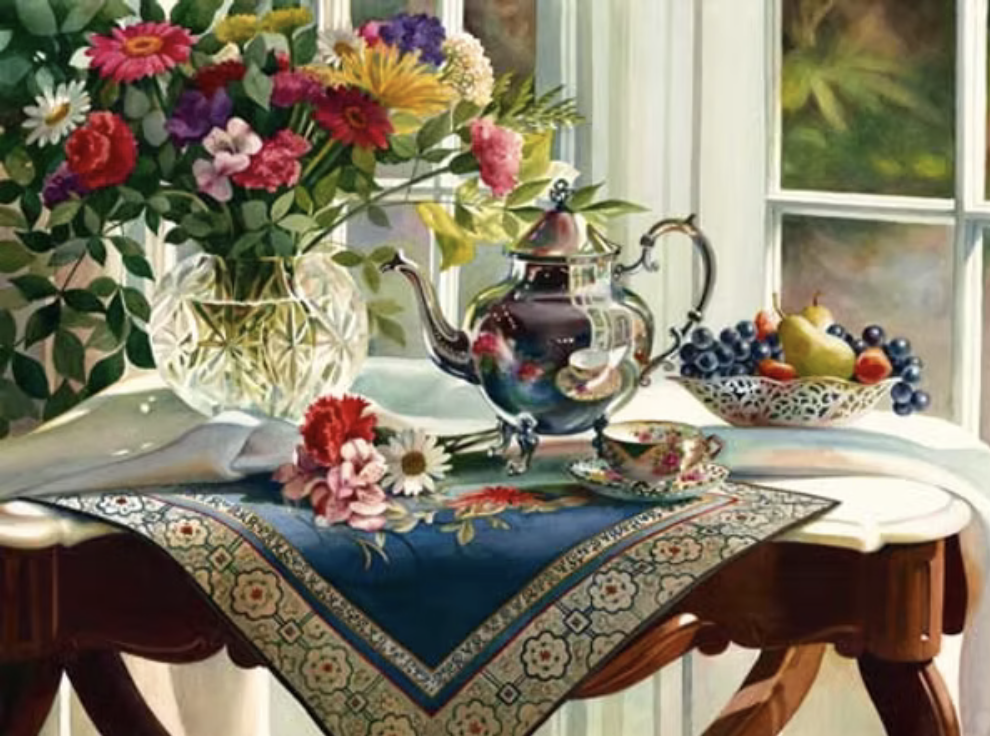 A floral arrangement of colorful flowers in a glass vase, a porcelain teapot with floral patterns, a matching teacup, a bowl of assorted fruits including pears, grapes, and apricots, on a decorative tablecloth on a wooden table near a window.