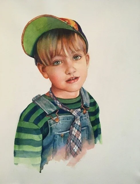 A young boy with brown hair and green eyes wearing a green and navy striped shirt, denim overalls, a plaid scarf, and a colorful cap tilted to the side.
