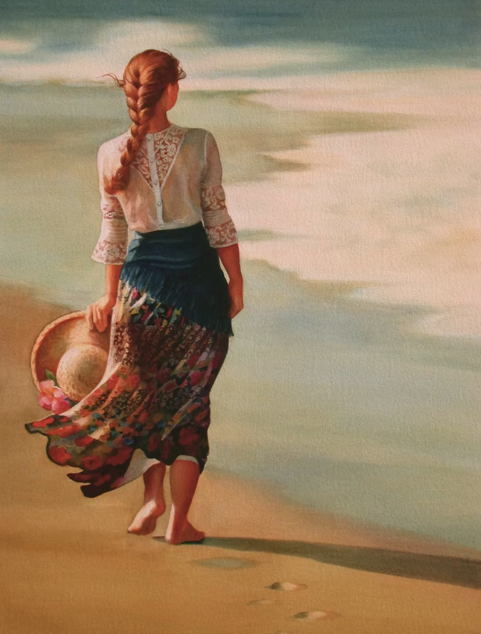 A woman with a red braid walks barefoot on the beach, carrying a straw hat with pink flowers in her hand. She wears a sheer lace blouse and a flowing colorful skirt, with waves in the background.