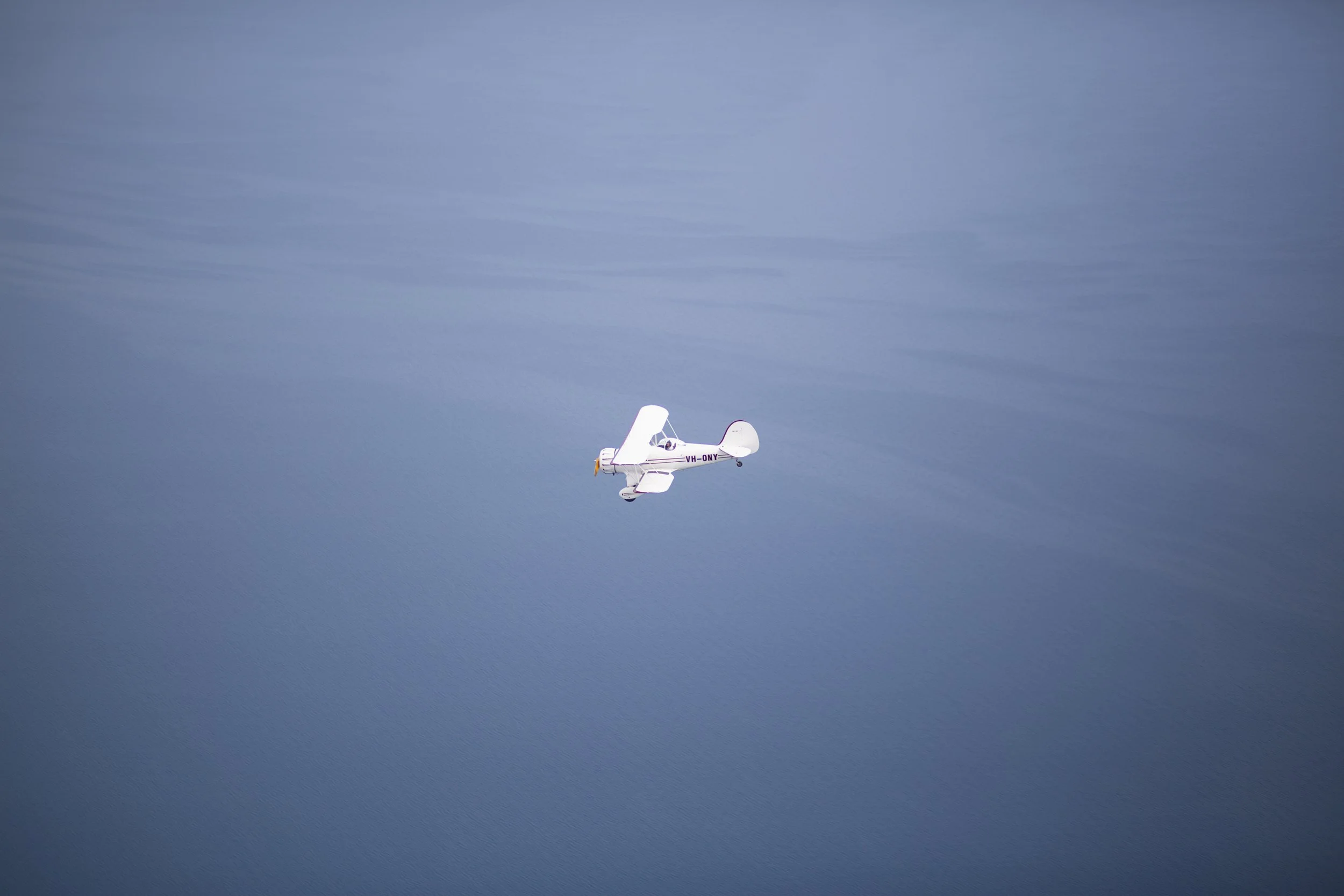 Un petit avion blanc vole dans un ciel bleuté avec quelques nuages