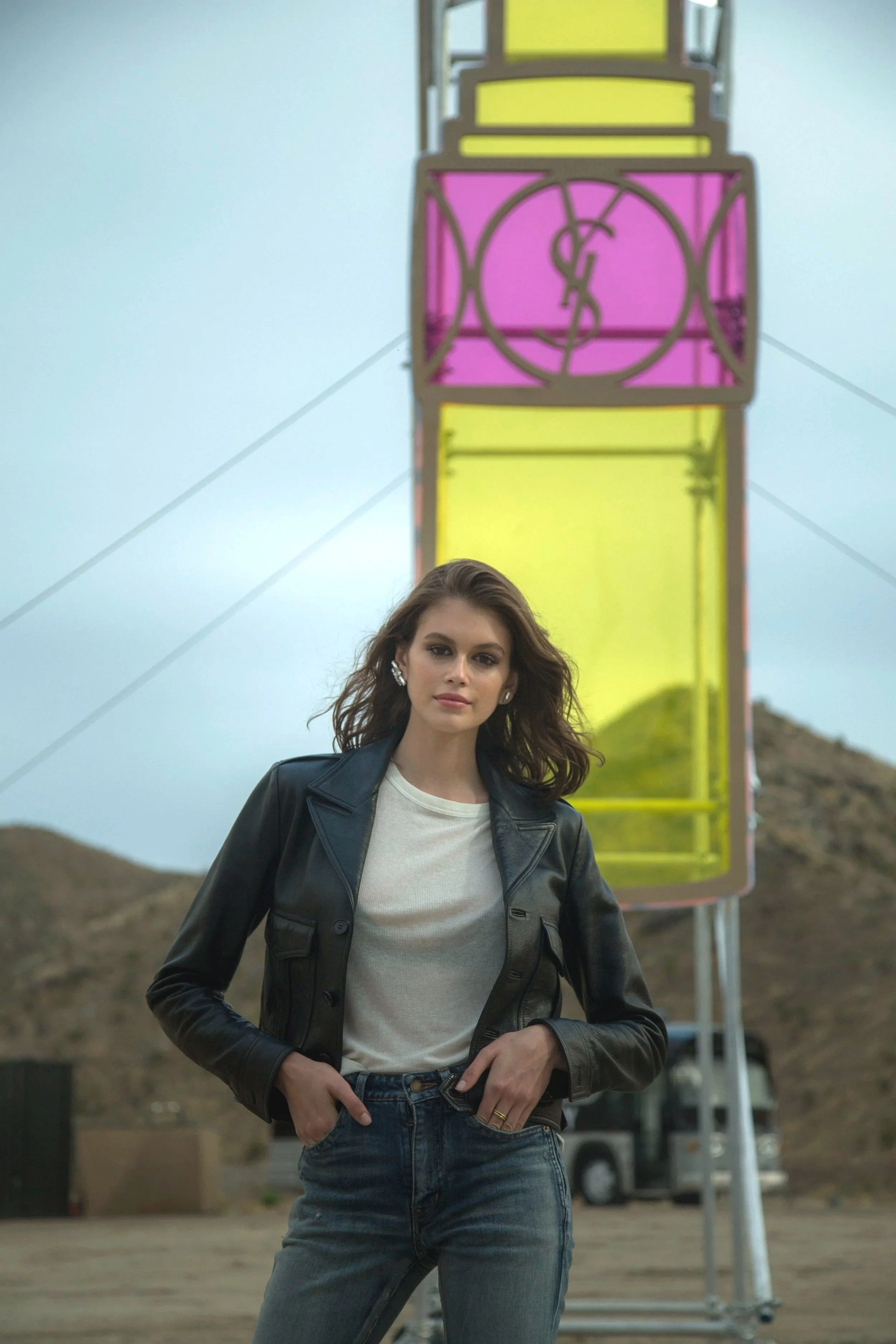 Jeune femme posant devant un panneau lumineux coloré dans un paysage désertique.