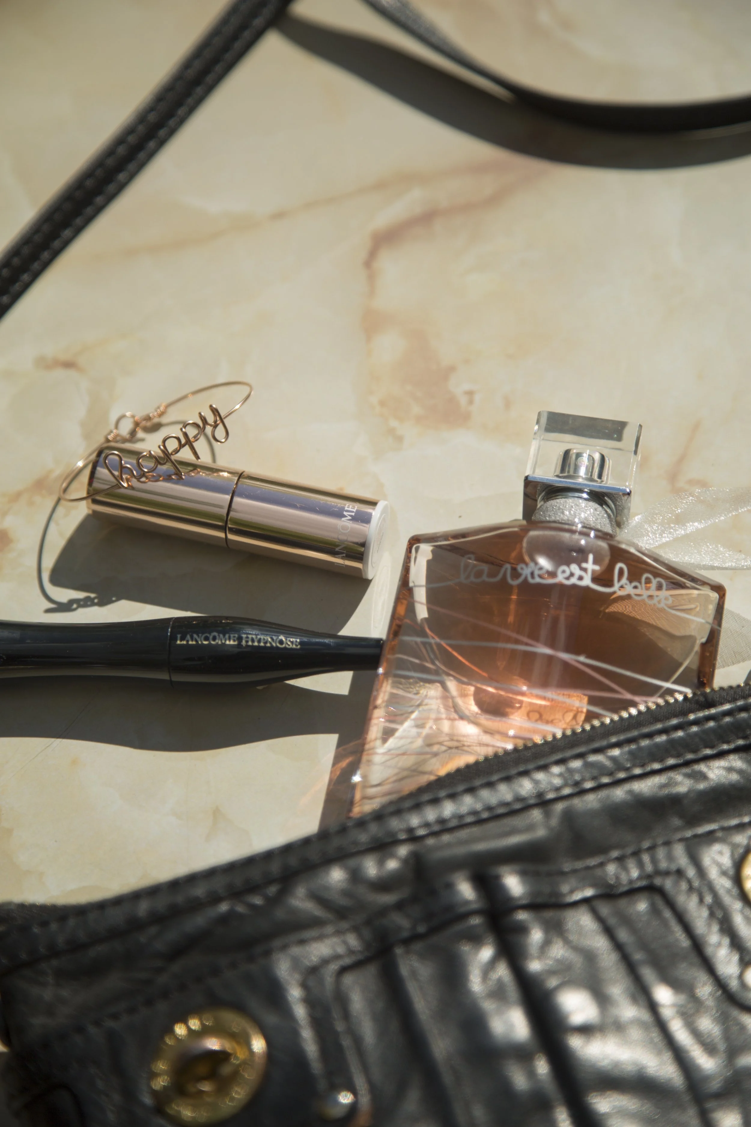 Trousseau de maquillage avec un rouge à lèvres, un parfum et un pinceau à maquillage dans un sac en cuir noir.