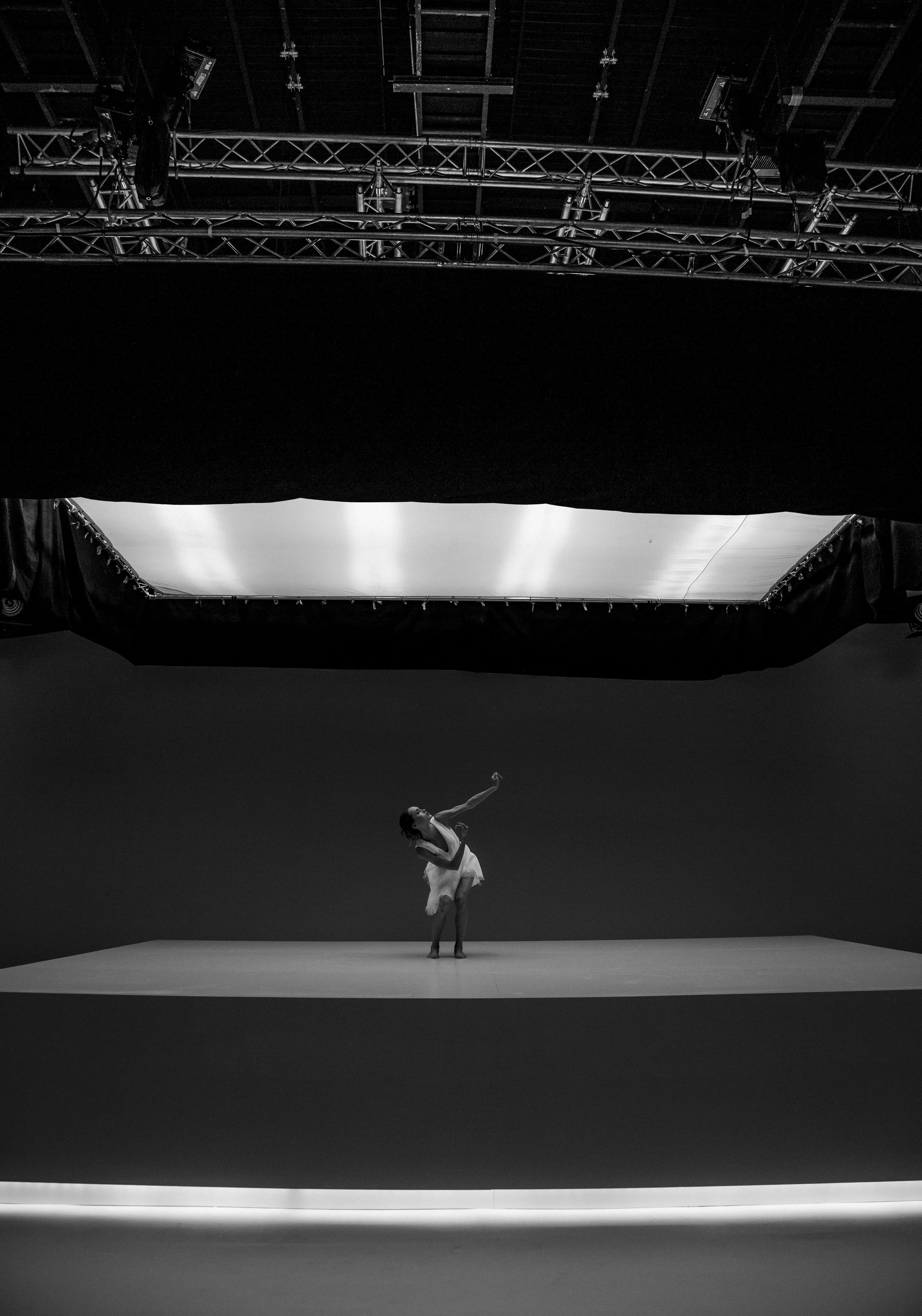 Une danseuse en aquamarine robe sur scène avec lumière tamisée, en studio de spectacle.