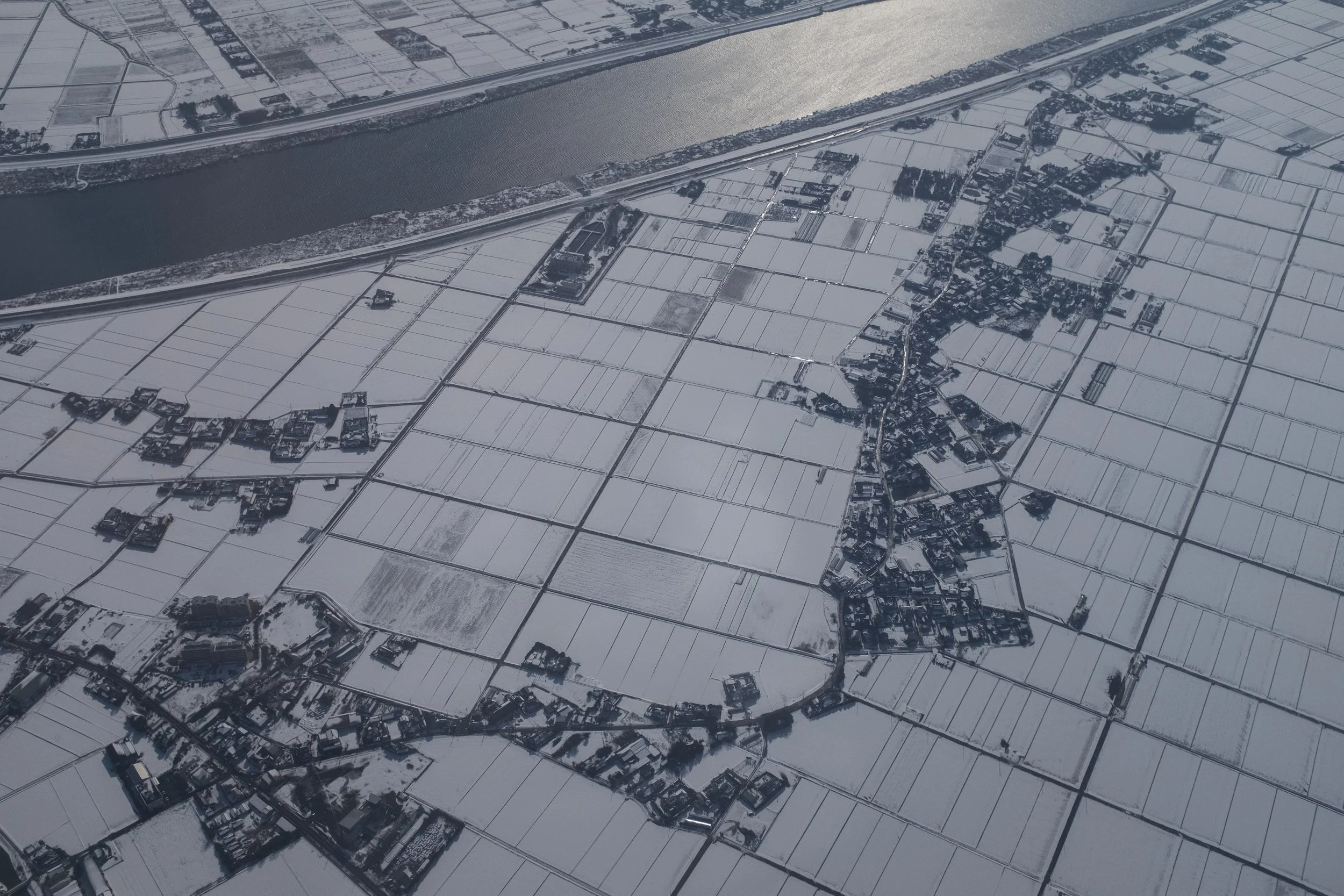 Paysages agricoles enneigés avec une rivière au centre, vues aériennes.