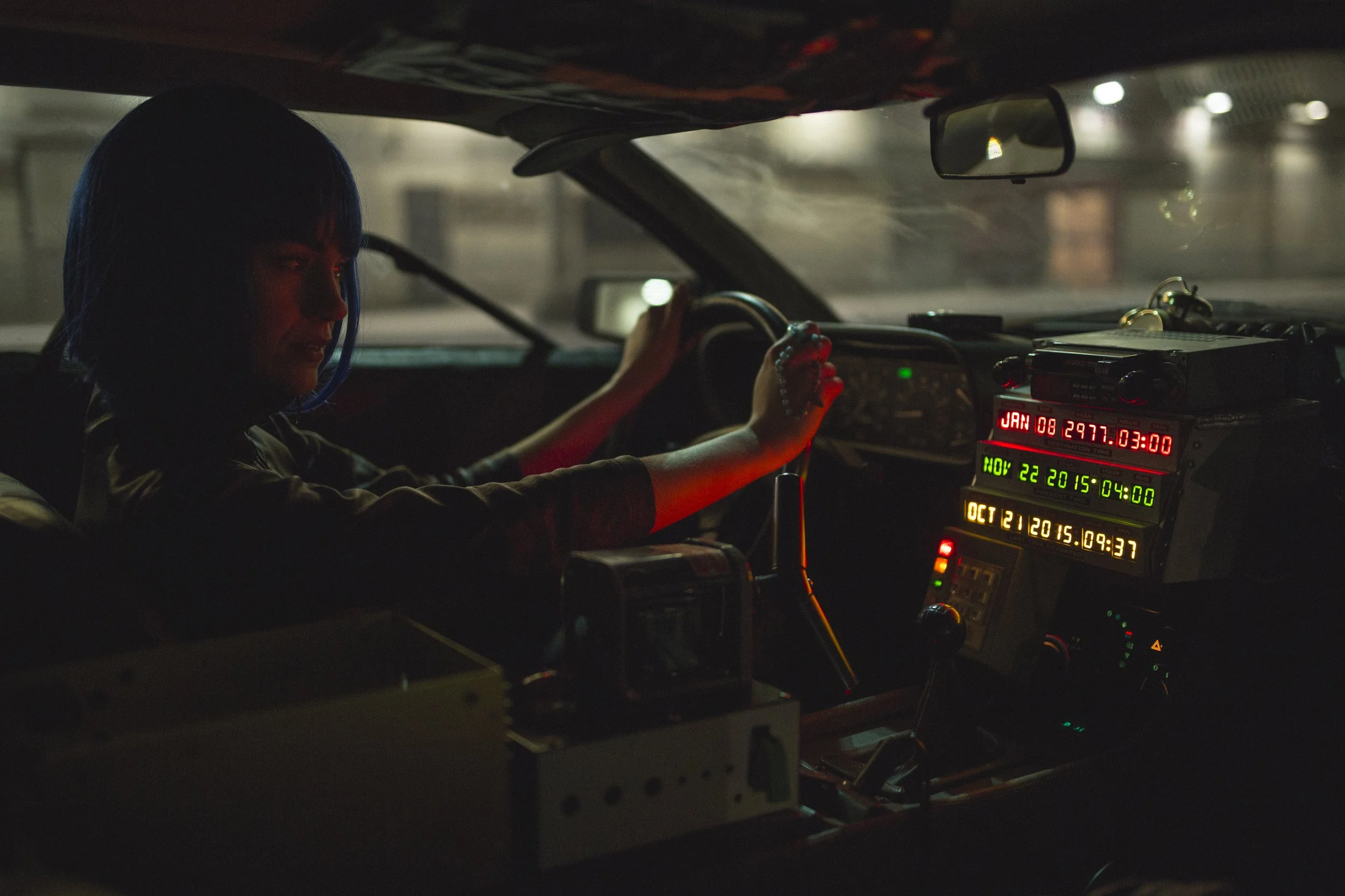 Personne dans le conducteur d'un véhicule, intérieur sombre, affichages numériques lumineux sur le tableau de bord, vue de nuit.
