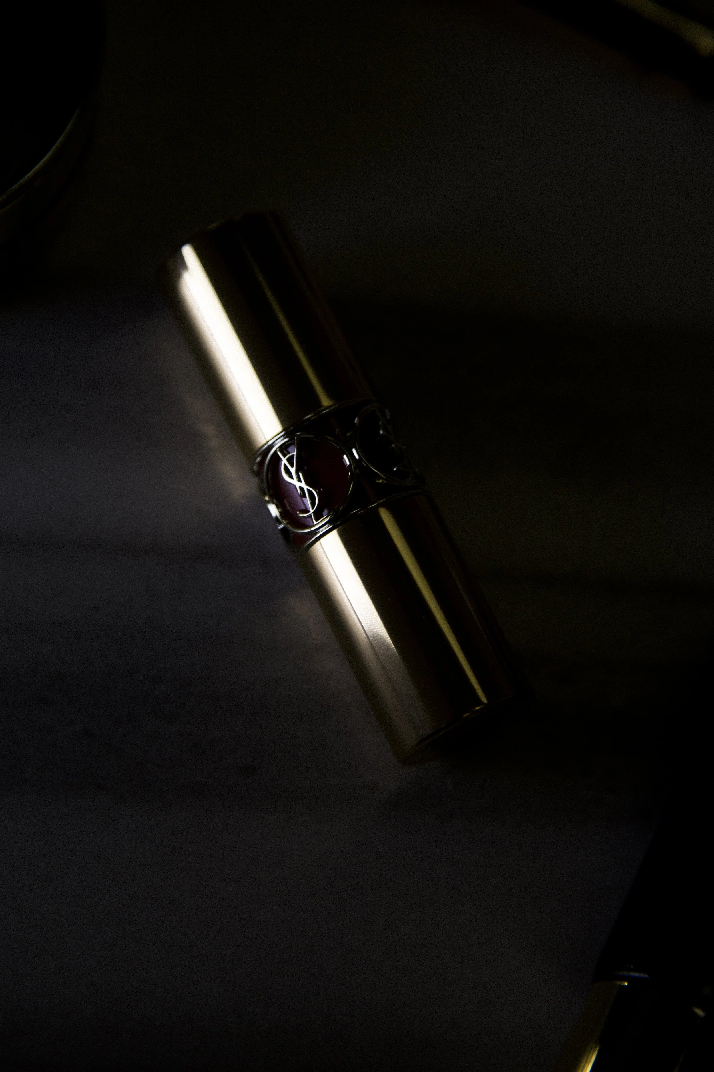 Un parfum de Yves Saint Laurent avec un bouchon métallique brillant sur fond noir.