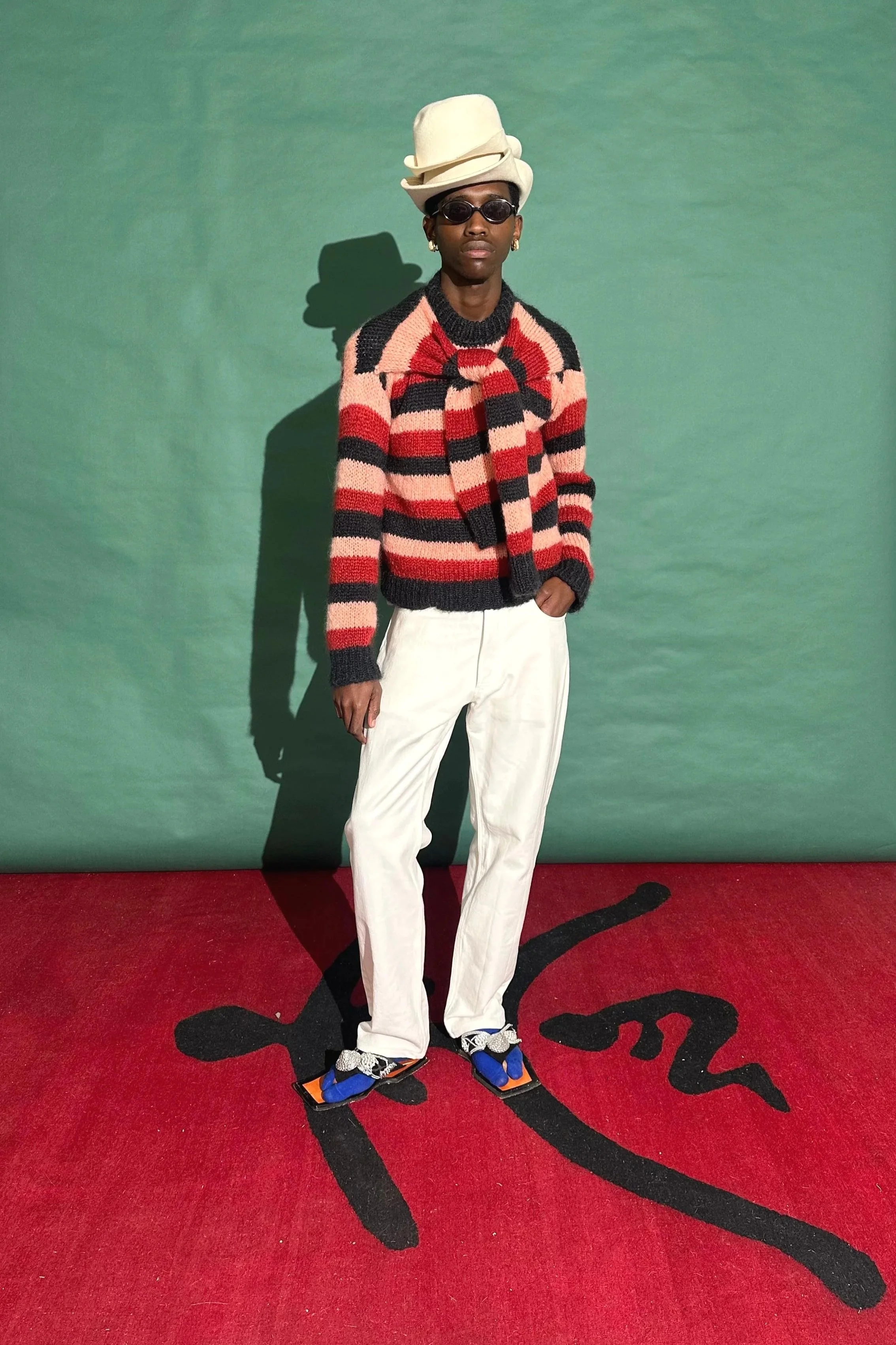 Model wearing a colourful striped mohair sweater and a small stack of hats. The sweater was made as a collaboration between Hannelie Bekker | Wrapt Knitwear and Wanda Lephoto.
