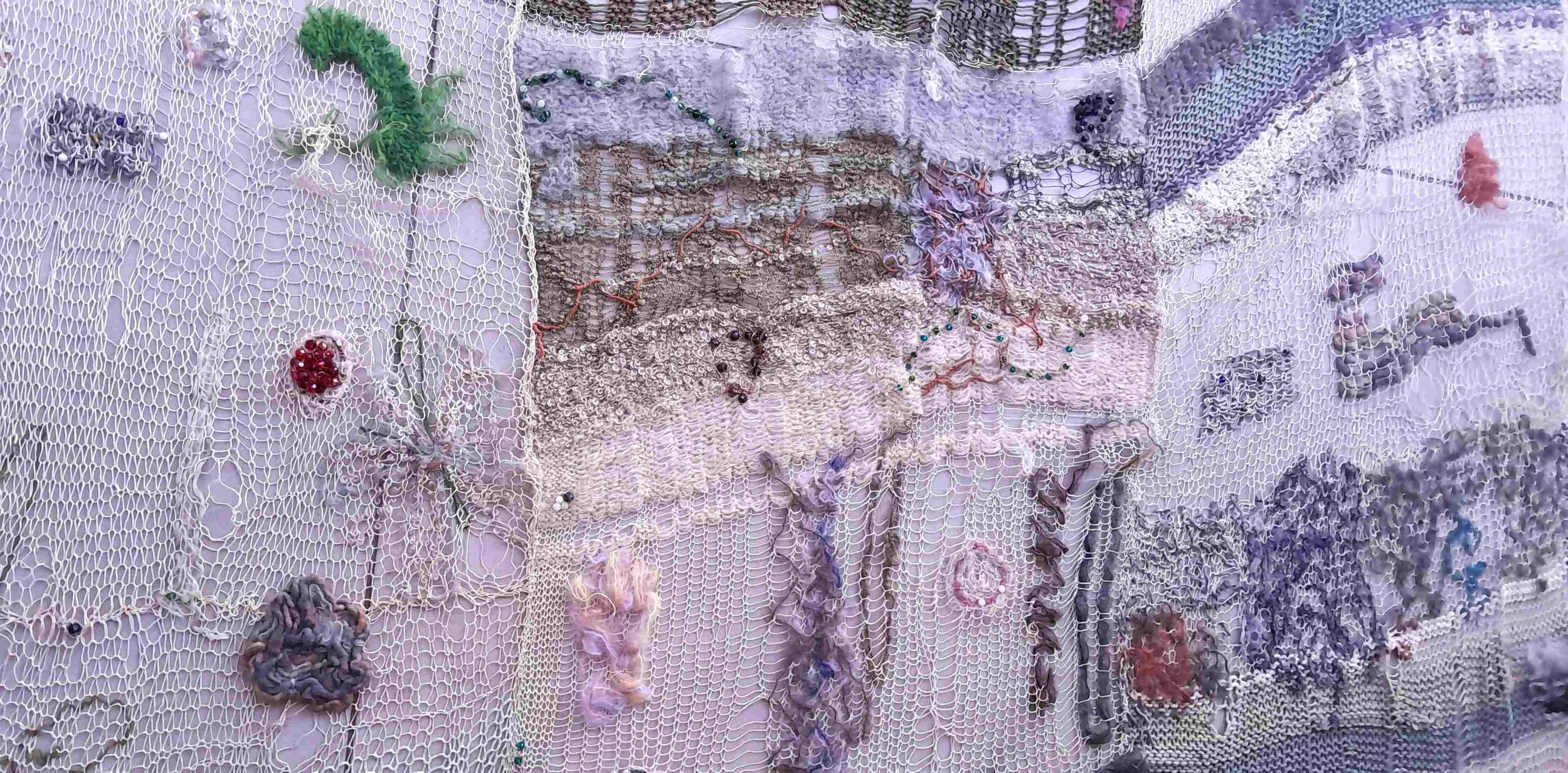 A patchwork textile wall hanging with various fabrics, beads, and embellishments sewn onto a netted base fabric.
