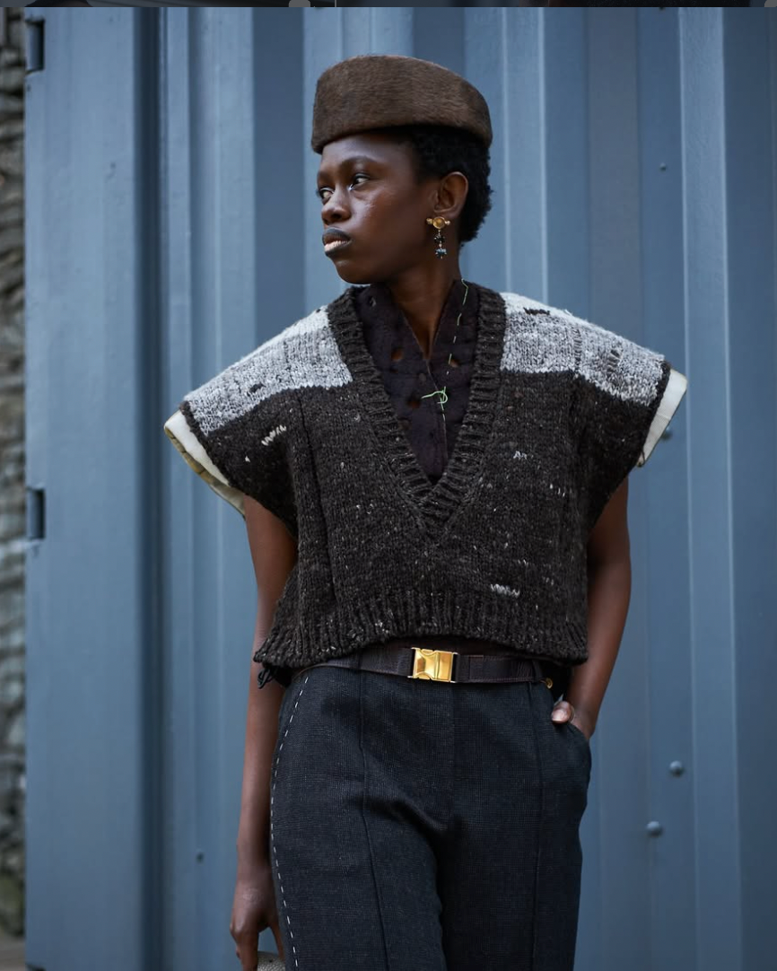 A woman wearing a a sleeveless vest knitted in black, gray and off-white handspun merino wool.