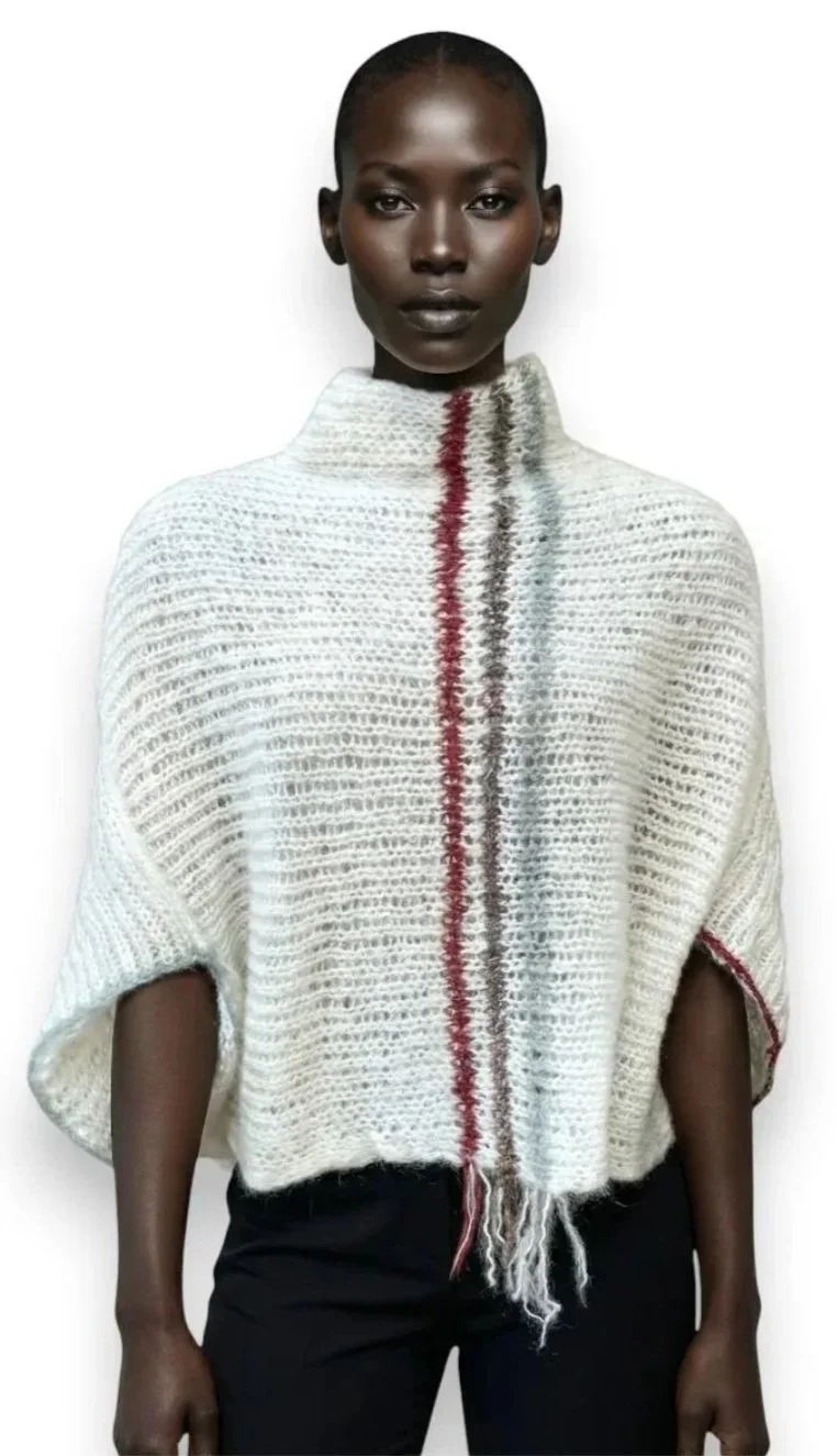 A model wearing a loose white cocoon-shaped knitted sweater with red, gray, and black vertical stripes. The sweater was made by Wrapt Knitwear for Aafricaa Store.