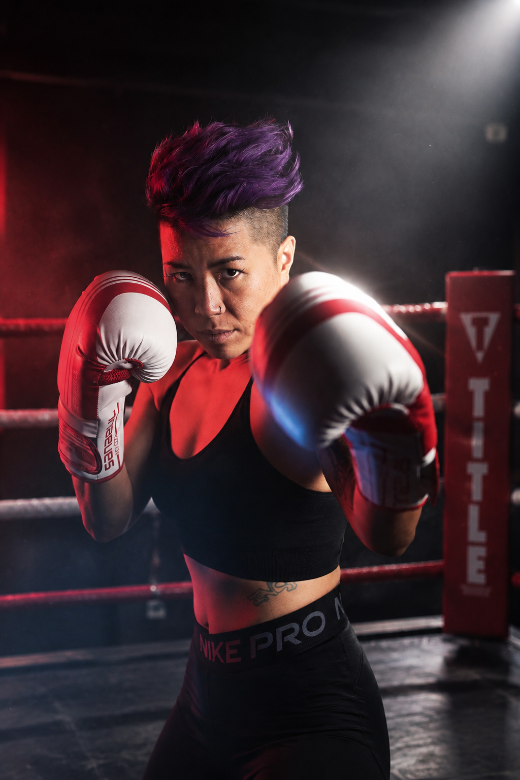 Boxer posing with raised gloves in a dramatically lit boxing ring