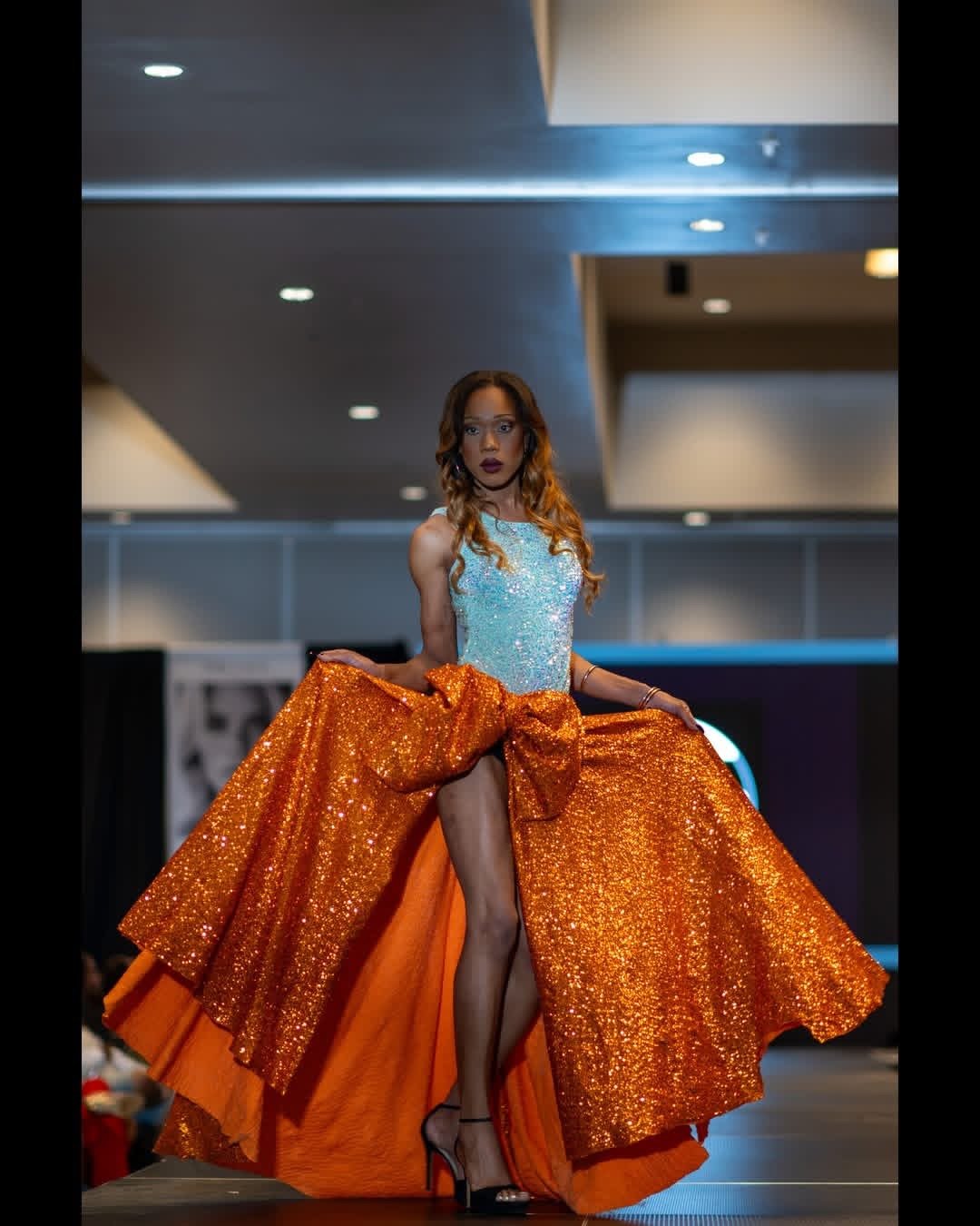 Runway photograph of a blue top and flowing orange skirt
