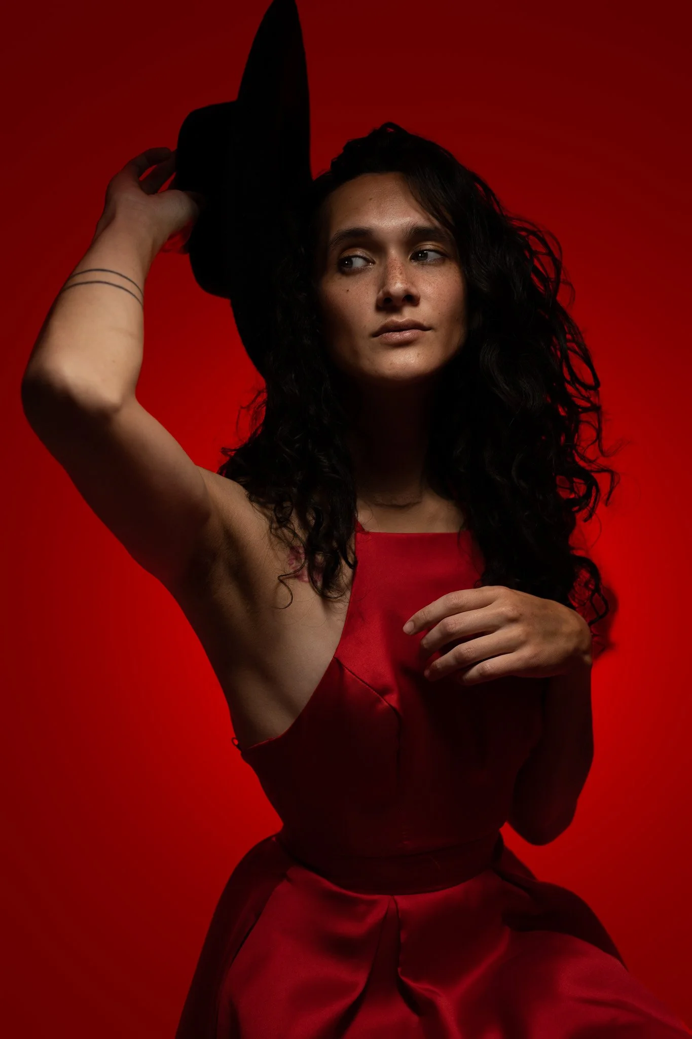 Creative studio portrait of a woman in a red dress against a red backdrop