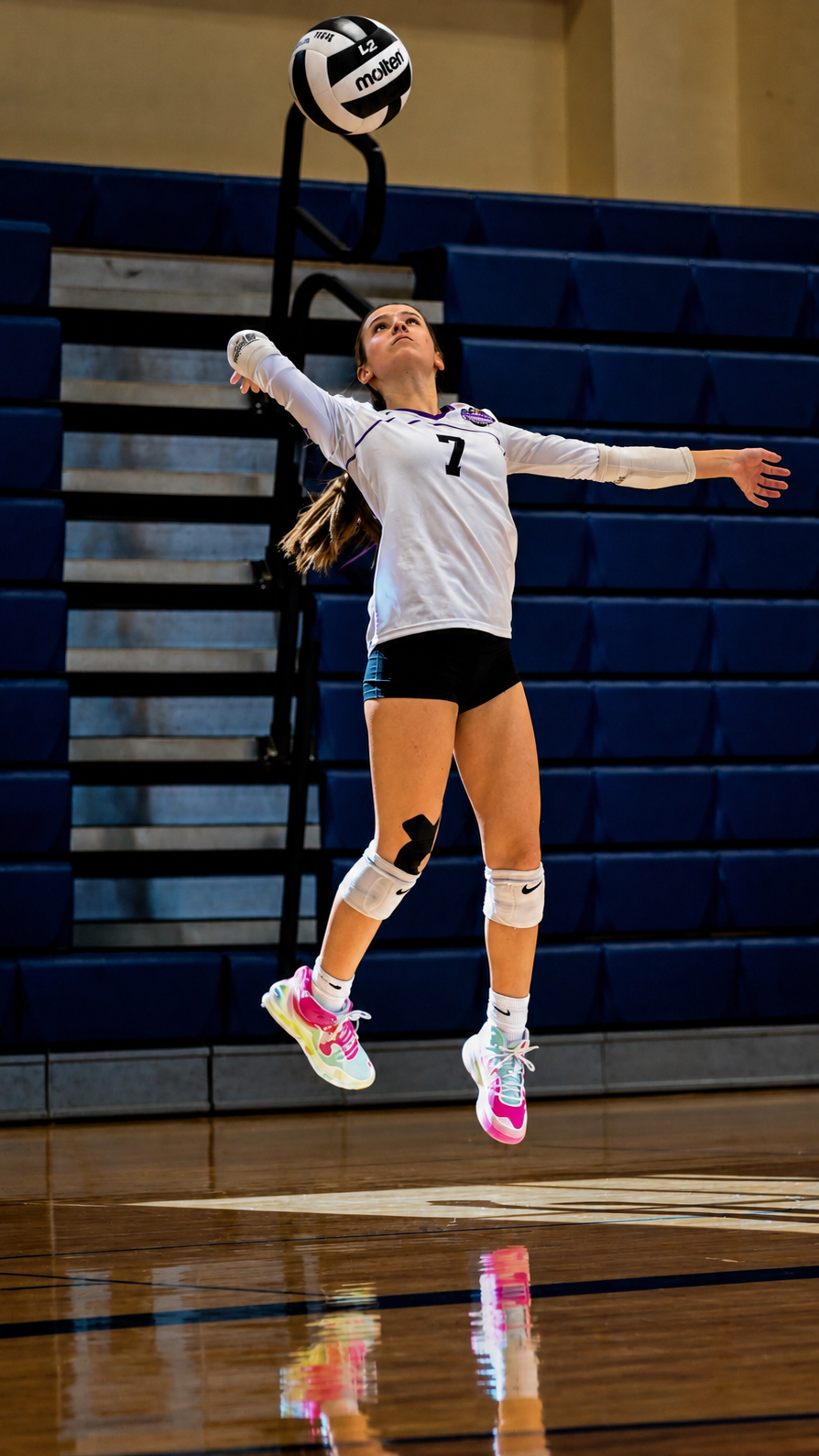 Volleyball player jumping to serve during an indoor match
