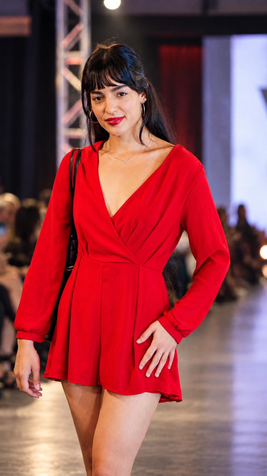 Runway model wearing a red long-sleeved romper