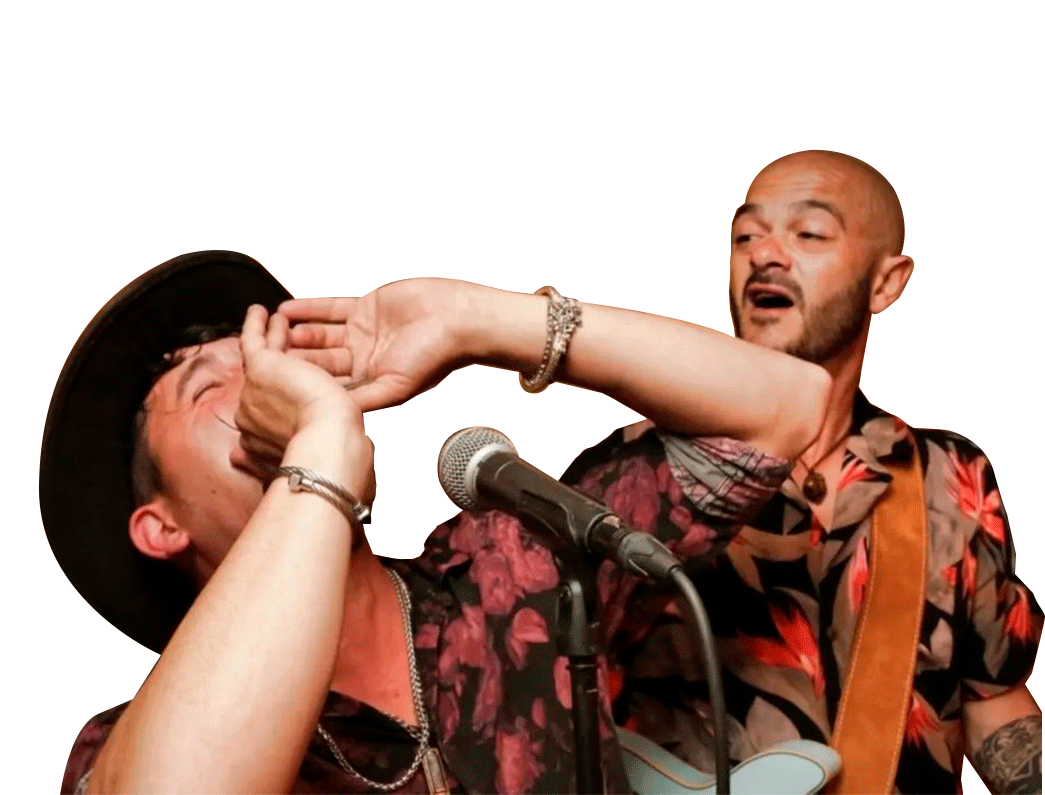 Dos hombres en un escenario de música, uno con sombrero y el otro con barba y peinado calvo, involucrados en una pelea con expresiones faciales de angustia y enojo, con un micrófono y una guitarra visible.