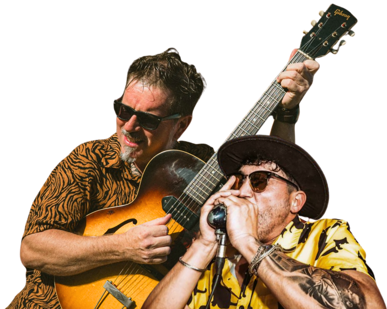 Dos hombres tocando música: uno con gafas de sol y camisa con estampado de tigre, tocando la guitarra; otro con sombrero y camisa amarilla con estampado de animales, cantando en un micrófono.