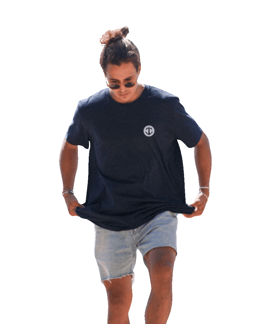 Persona con camiseta azul, pantalones cortos de mezclilla, gafas de sol y peinado recogido, caminando y mirando hacia abajo.
