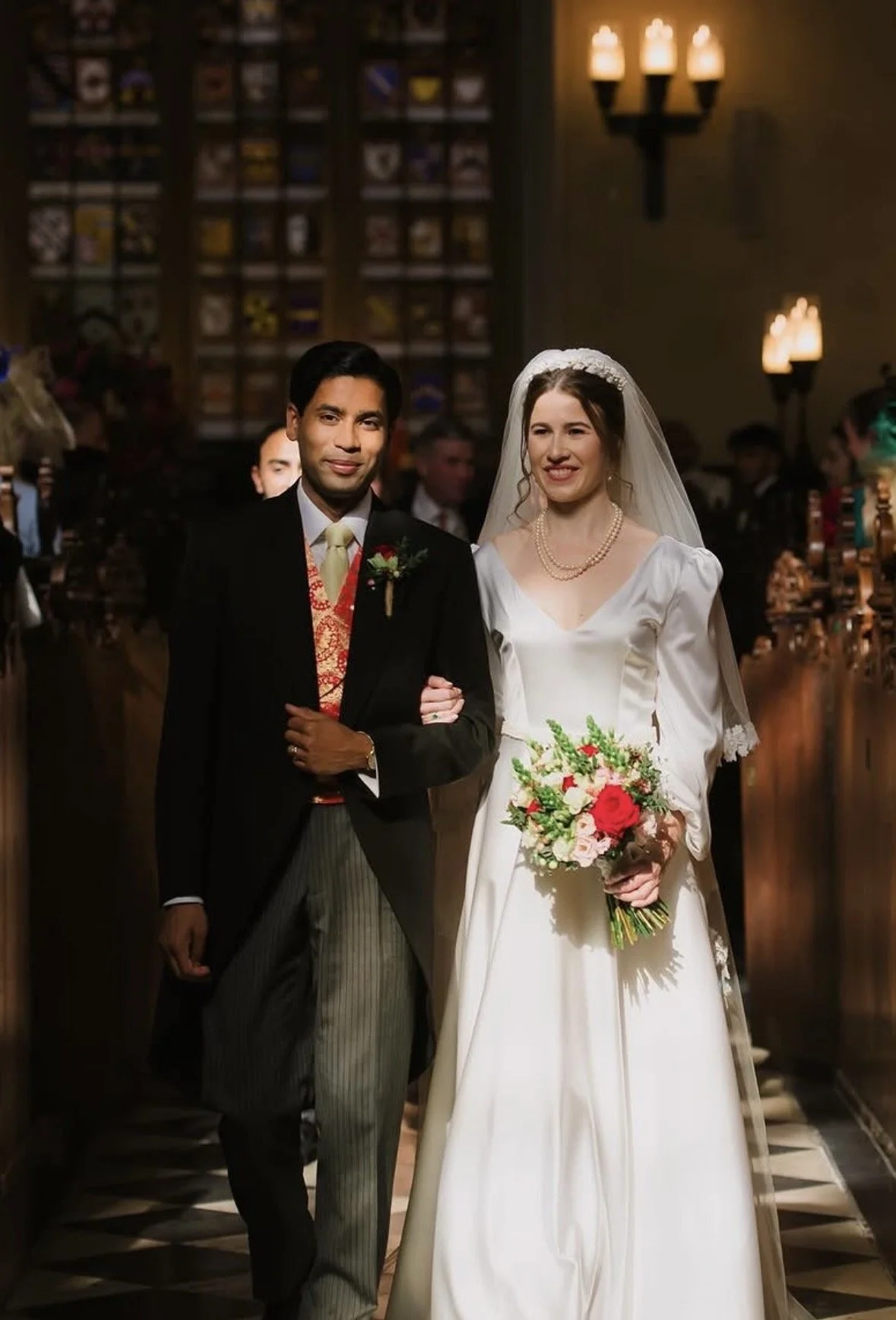 A bride and groom walking down the aisle during a wedding ceremony in a church, with guests watching.