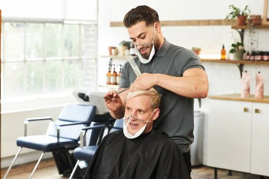 A man getting a haircut from a barber in a modern salon.