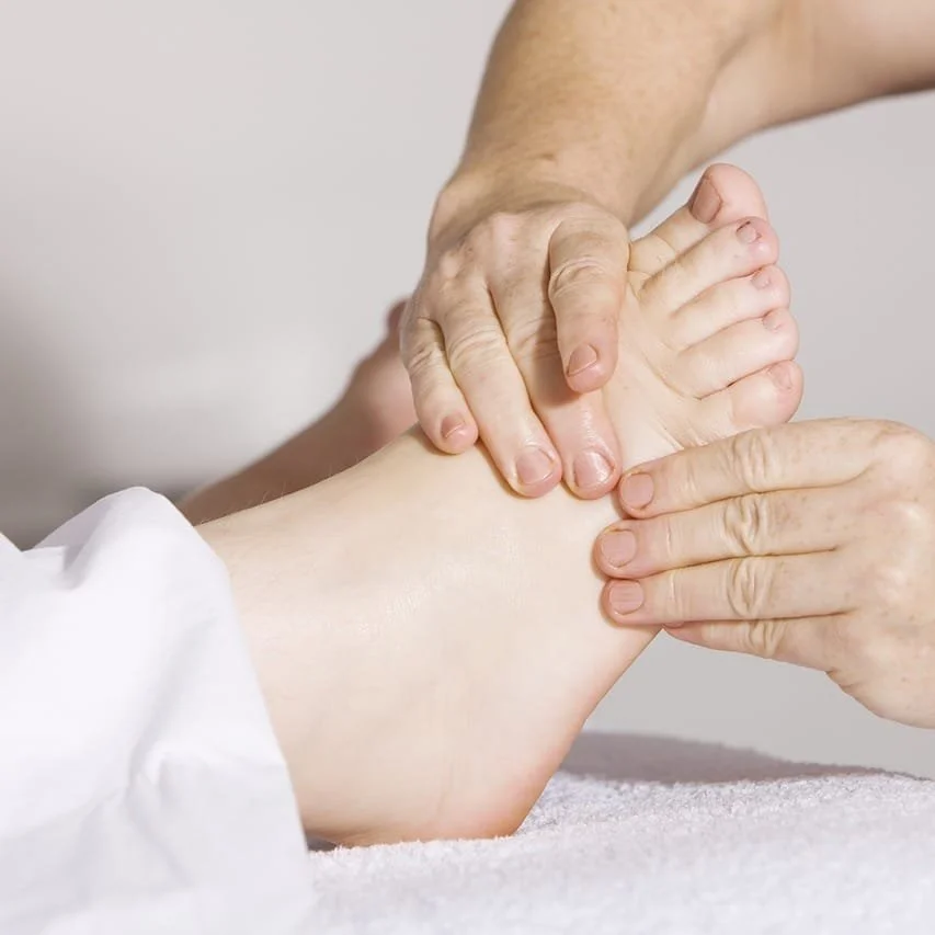 Close-up of a massage therapist applying pressure to a person's foot during a massage.