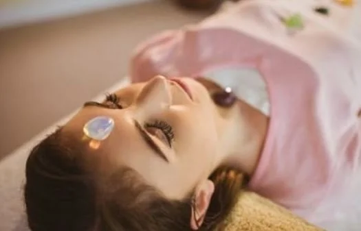 Woman lying down with closed eyes, receiving a forehead acupuncture treatment.