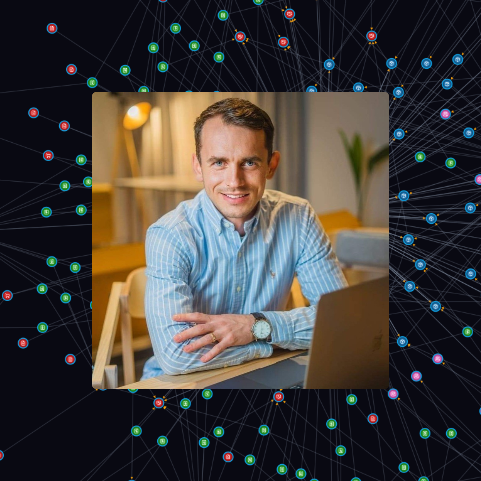 Close-up of a smiling man with blue eyes, wearing a blue striped shirt, sitting at a wooden table indoors, with a lamp and a plant in the background, overlaid on a digital network background of interconnected colored nodes and lines.