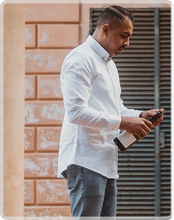 Man standing outdoors, celebrating with a bottle of wine.